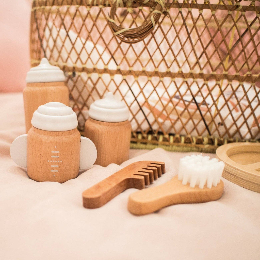 Wooden baby care products including bottles, brush, and comb on a soft surface with a woven basket in the background.